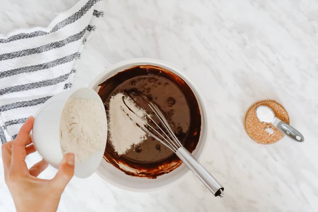 Mixing together brownie cookies with a whisk in a white bowl