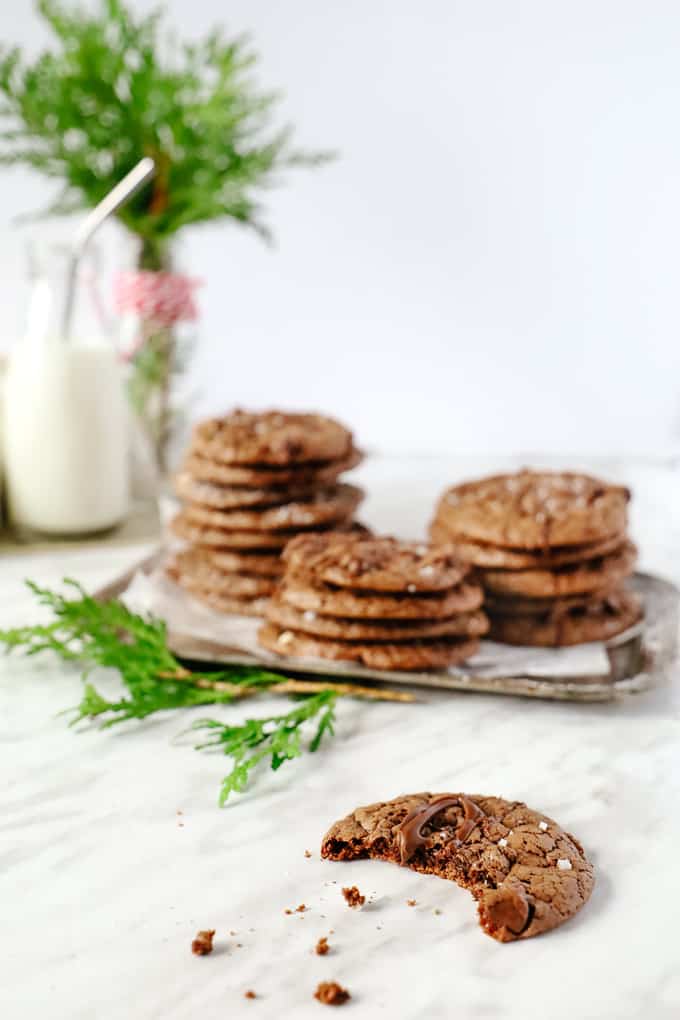 A bite out of a brownie cookie with others stacked in the background. 