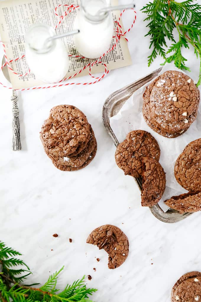 Milk in bottles, and a scattering of brownie cookies, one with a bite taken. 