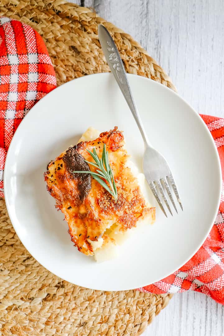 Overhead shot of Delmonico potatoes on a white plate with a fork. 