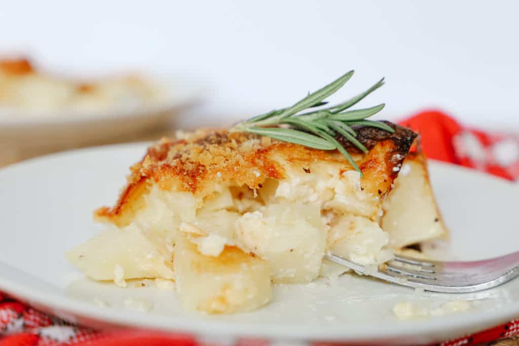 Servir en gros plan des pommes de terre Delmonico sur une assiette blanche avec une fourchette.