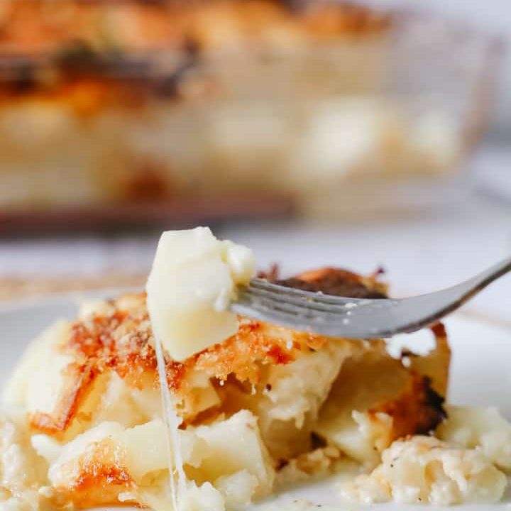 Close of a delmonico potatoes dish with a cheese pull on the potato