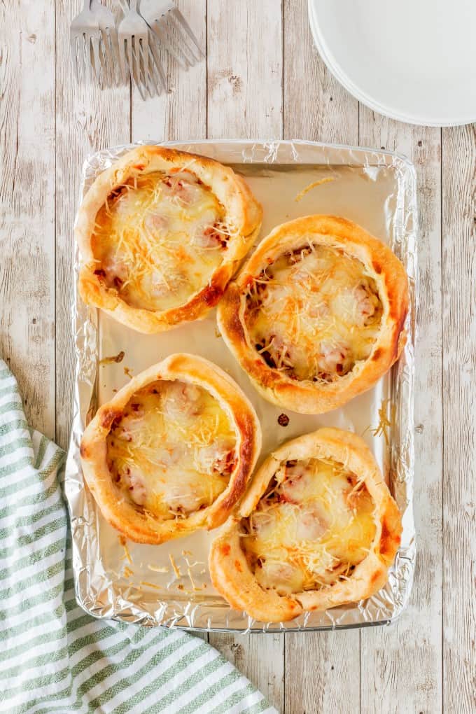 Four baked Copycat Olive Garden Pizza Bowls on a baking sheet.