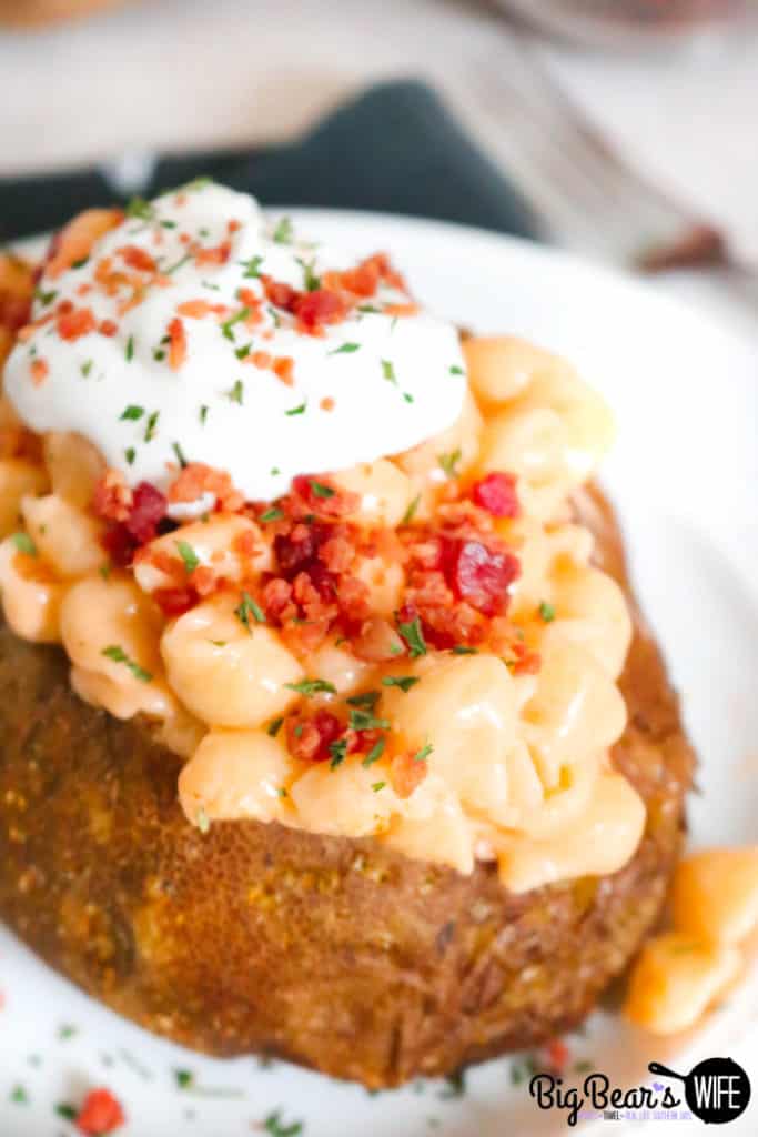 Loaded Mac and Cheese Stuffed Baked Potatoes with bacon bits and sour cream topping on a white plate