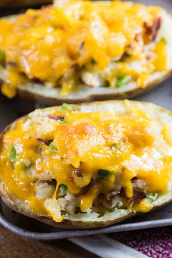 Stuffed baked potatoes on a cooking tray covered with melted cheese