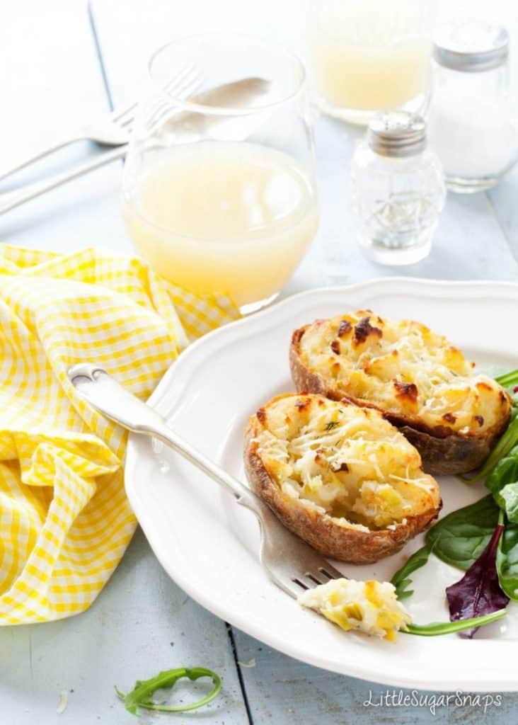 Cheesy Leek Baked Potatoes on a white plate with a fork and salad
