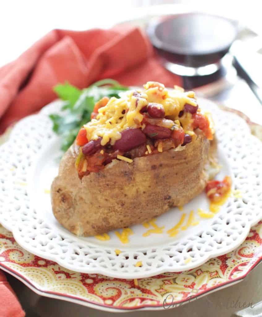 Baked potato with chili and melted cheese on a fancy white plate