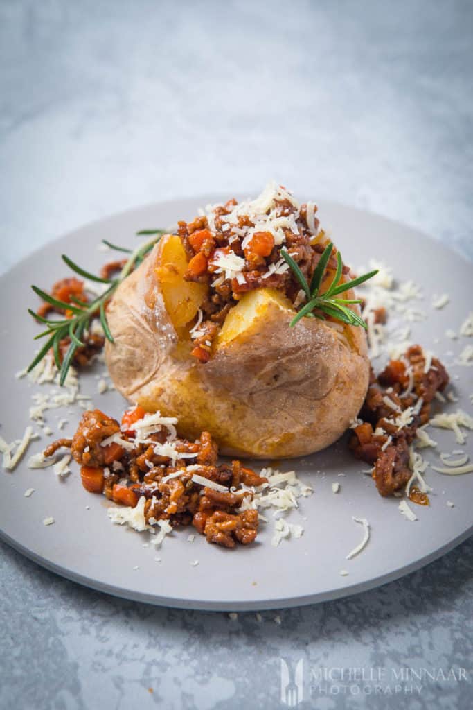 Savoury Mince Fill Baked Jacket Potatoes on a white plate with rosemary garnish
