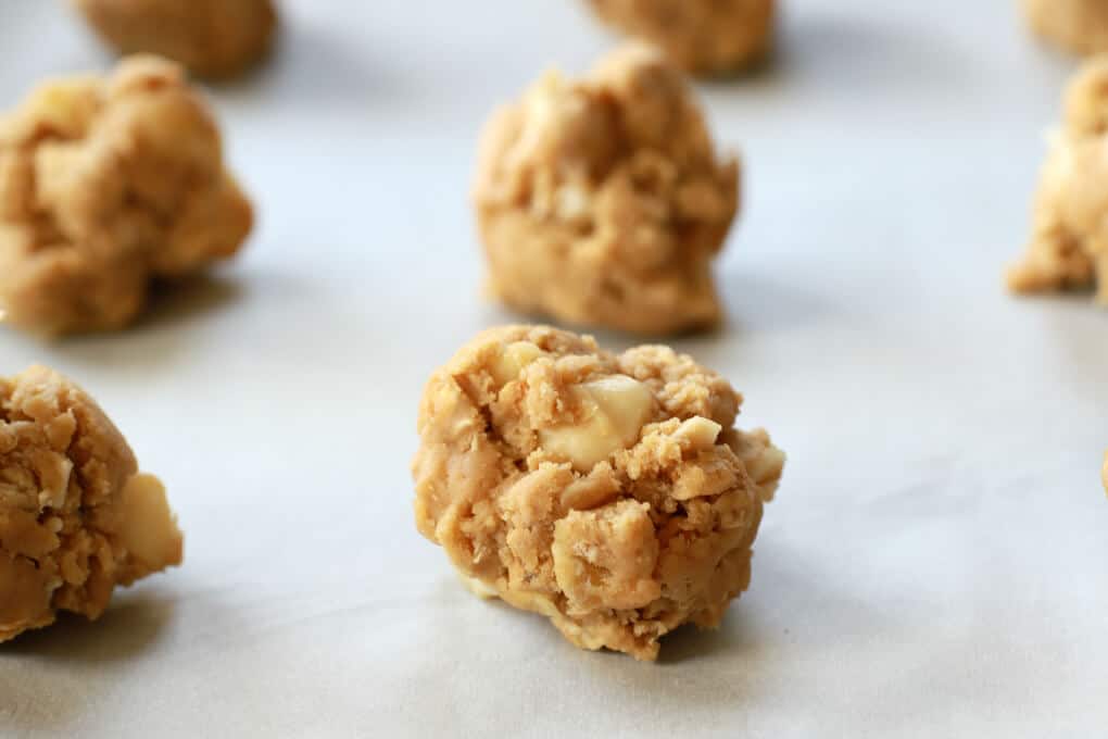 Raw cookie dough dropped on a piece of parchment.