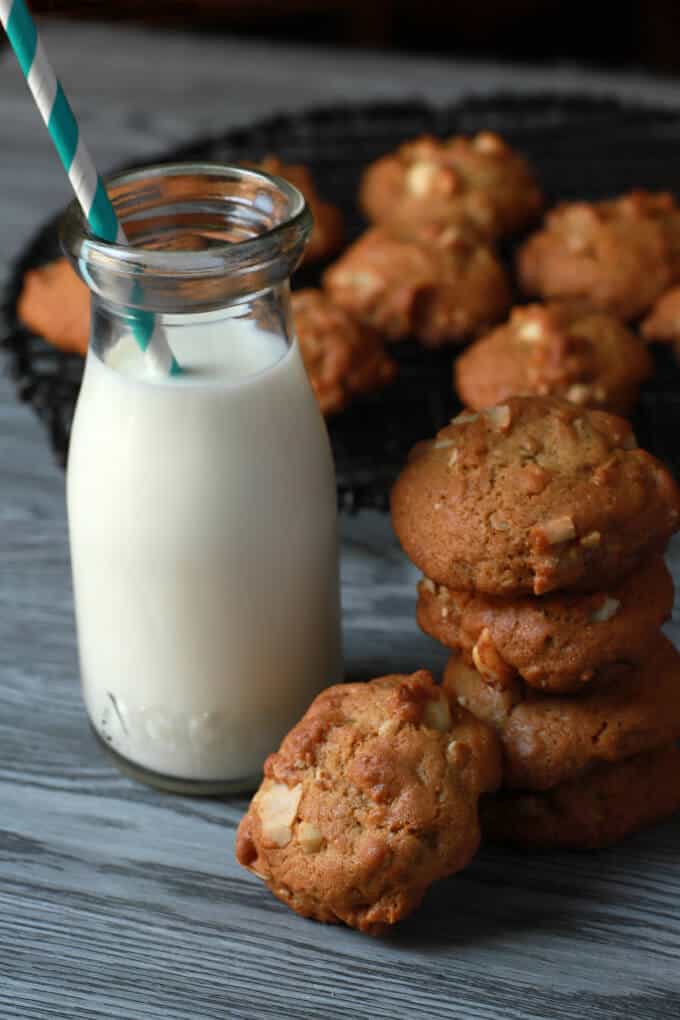 A stack of golden cookies next to a bottle containing milk and a straw.