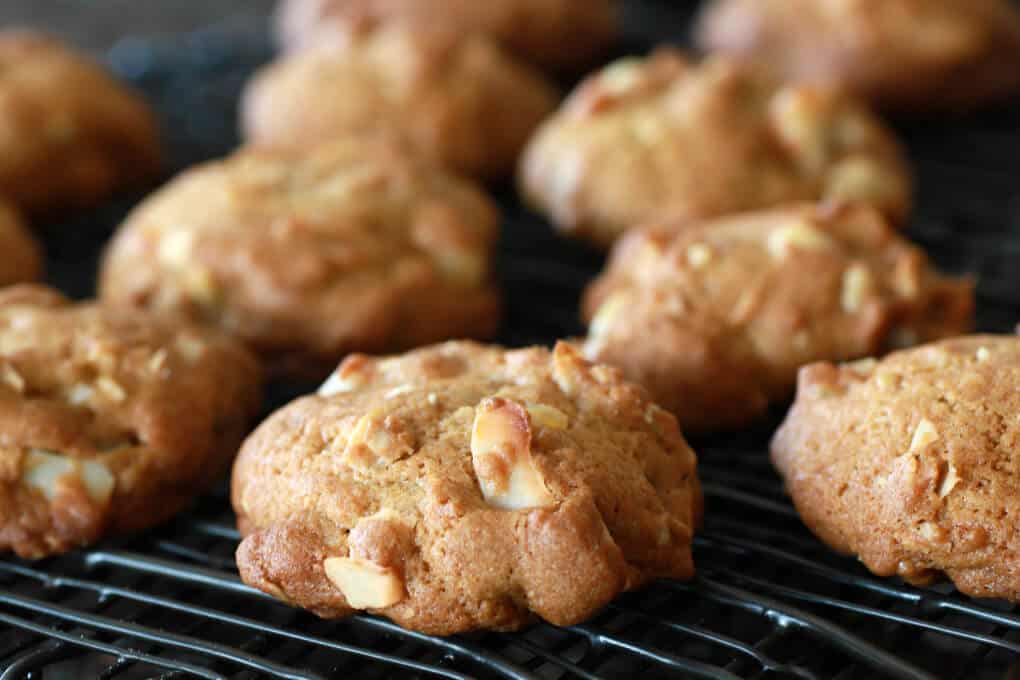 A golden baked cookie surrounded by more cookies on a black baking rack.