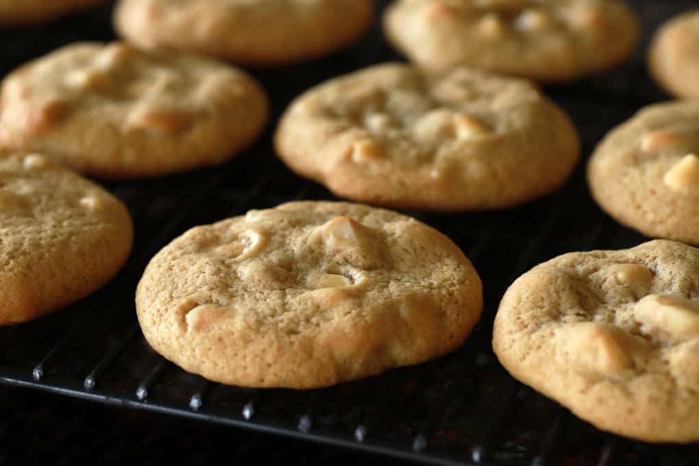 Golden baked cookies cooling on a black cookie rack.