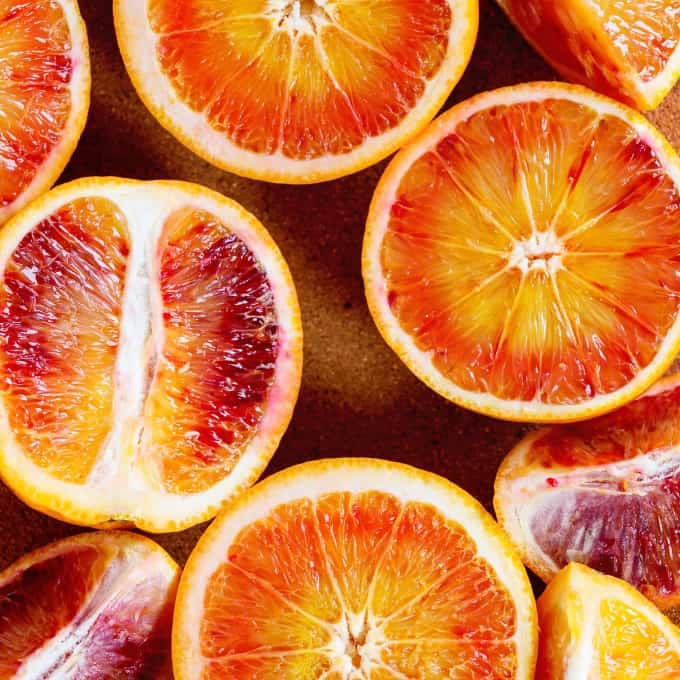 Close up of Sliced Sicilian Blood oranges fruits in brown clay plate. Top view. Square image