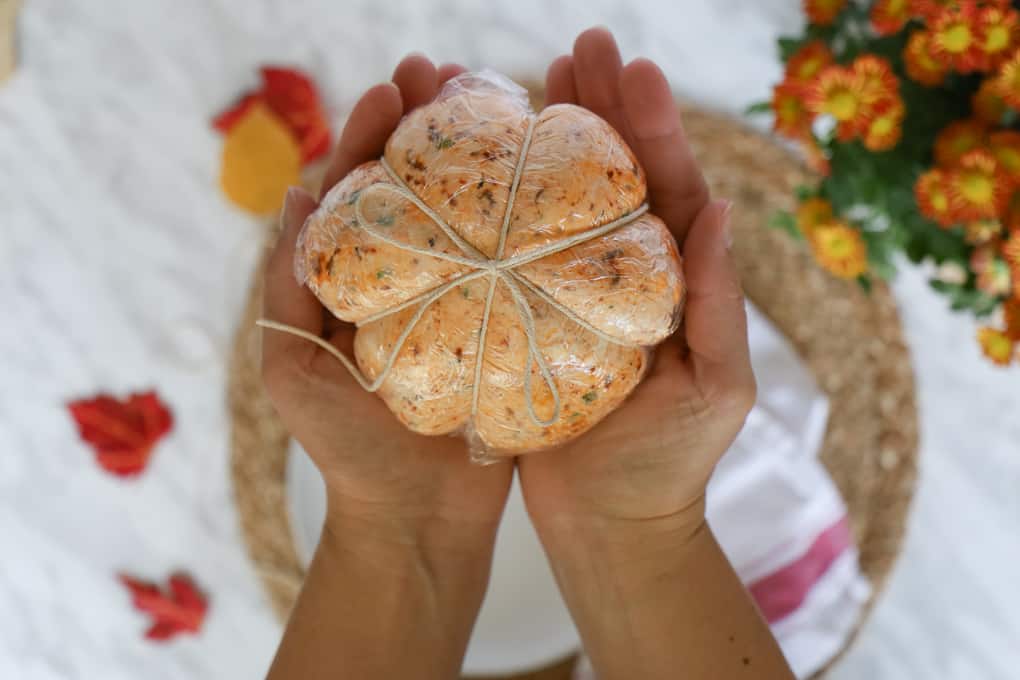 Showing how to wrap up a pumpkin cheese ball