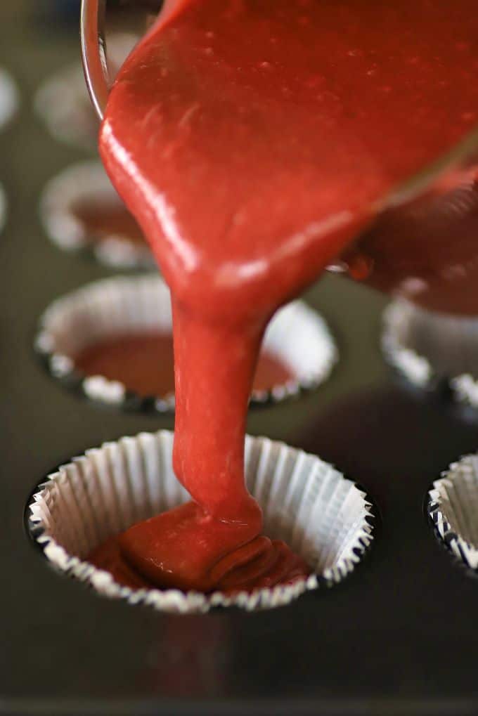 Red Velvet Batter being poured into a cupcake liner.
