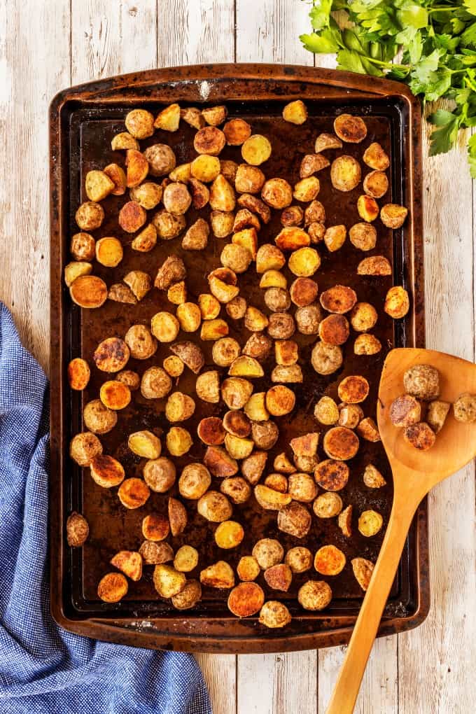 Extra Crispy Potatoes on a sheet pan with a wooden spoon. 