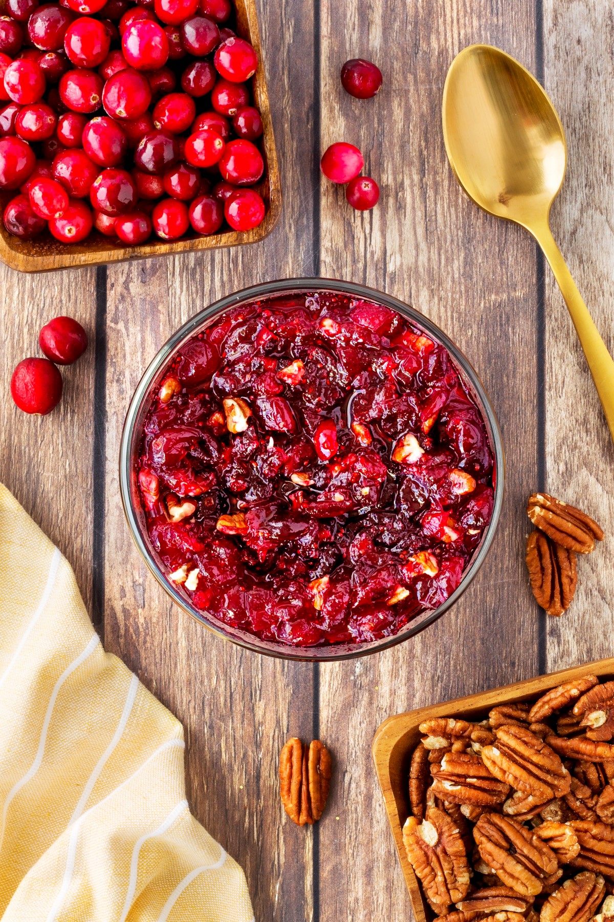 Overhead of cranberry sauce in a bowl with fresh cranberries and a gold spoon. 