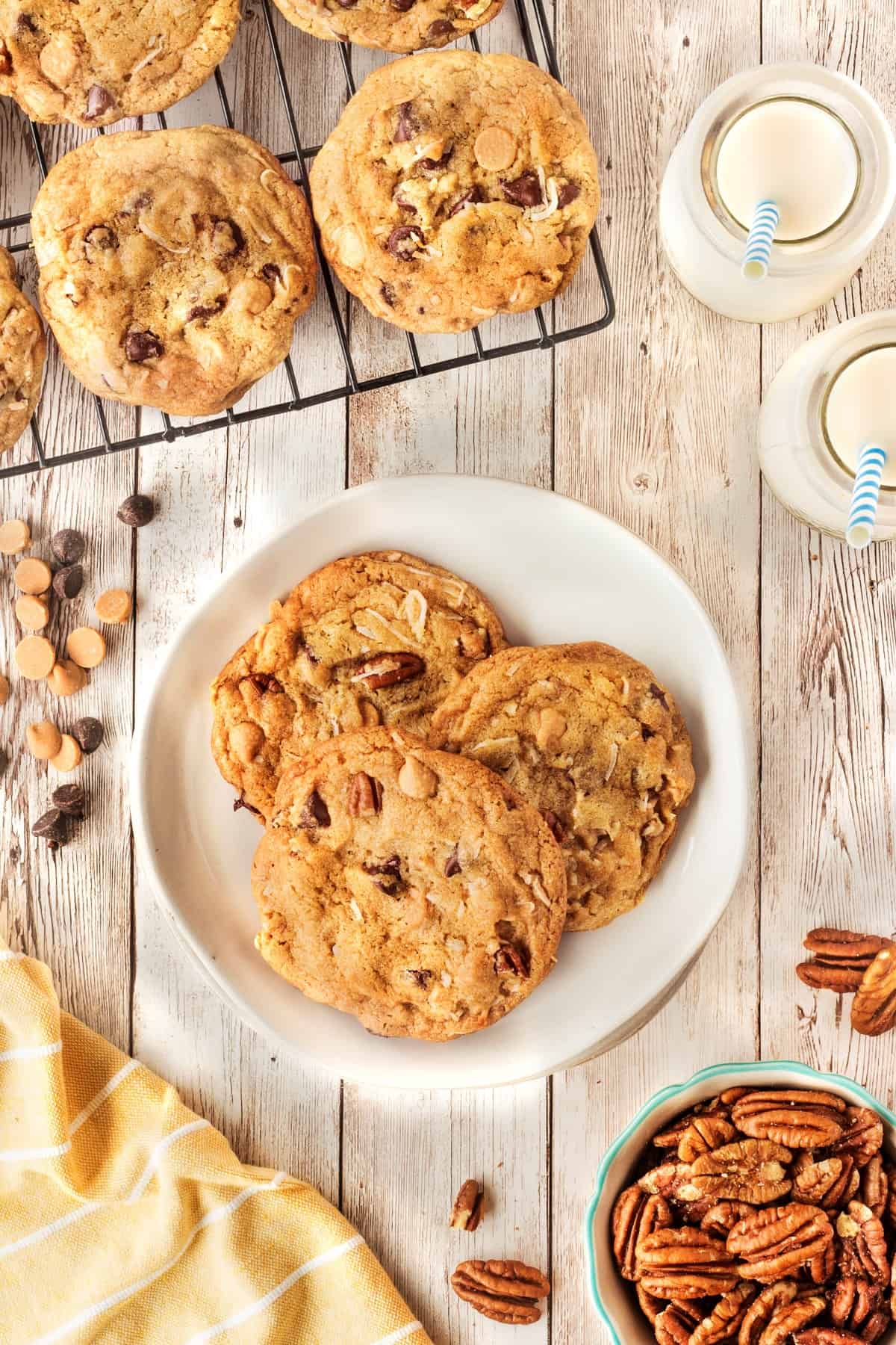 Overhead shot of Kitchen Sink Cookies on a plate plus a cooling rack with milk, chocolate chips and nuts scattered around. 