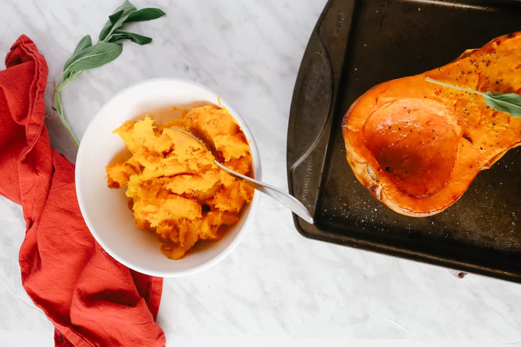 Roasted butternut squash on a baking sheet and more in a bowl. 