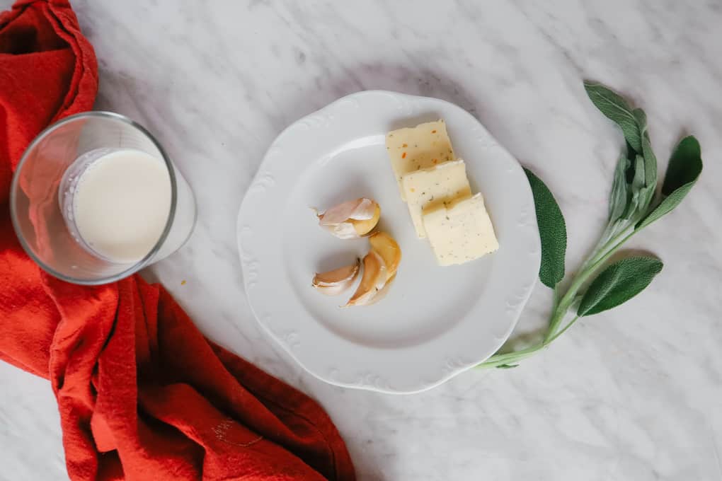 Garlic and butter on a plate with sage and cream in a cup