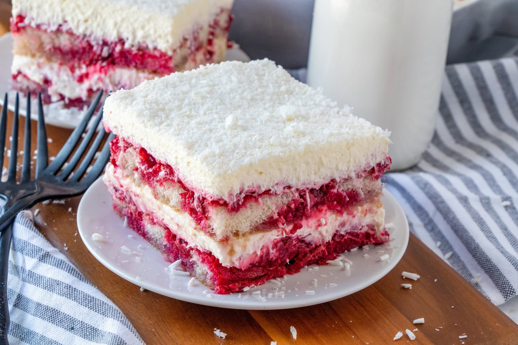 This White Chocolate Raspberry Tiramisu has a new twist that is light and refreshing. Layers of ladyfingers are dipped in a simple syrup orange liqueur and alternating with a white chocolate mascarpone whipped cream. It is like a slice of heaven. Slice of tiramisu on a plate.