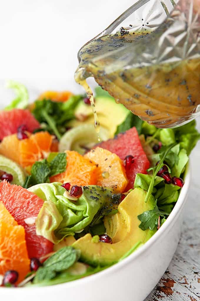 Pouring poppy seed dressing on salad