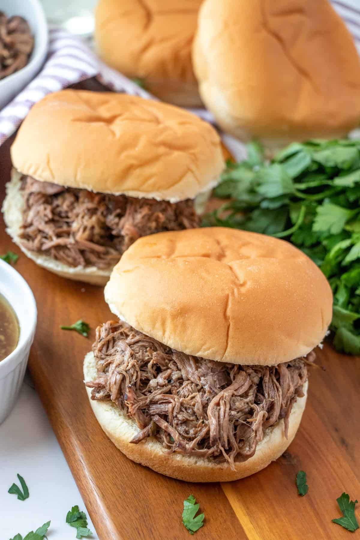 Two Slow Cooker Beef Dip sandwiches on a cutting board