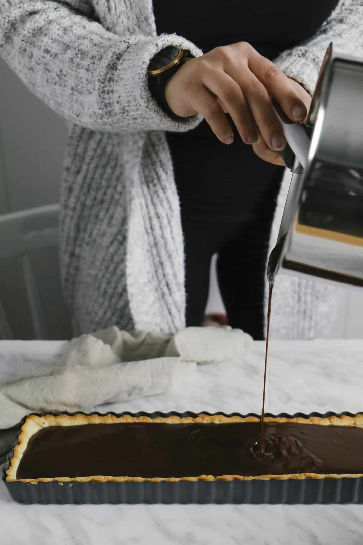 Pouring chocolate filling into a rectangle tart shell