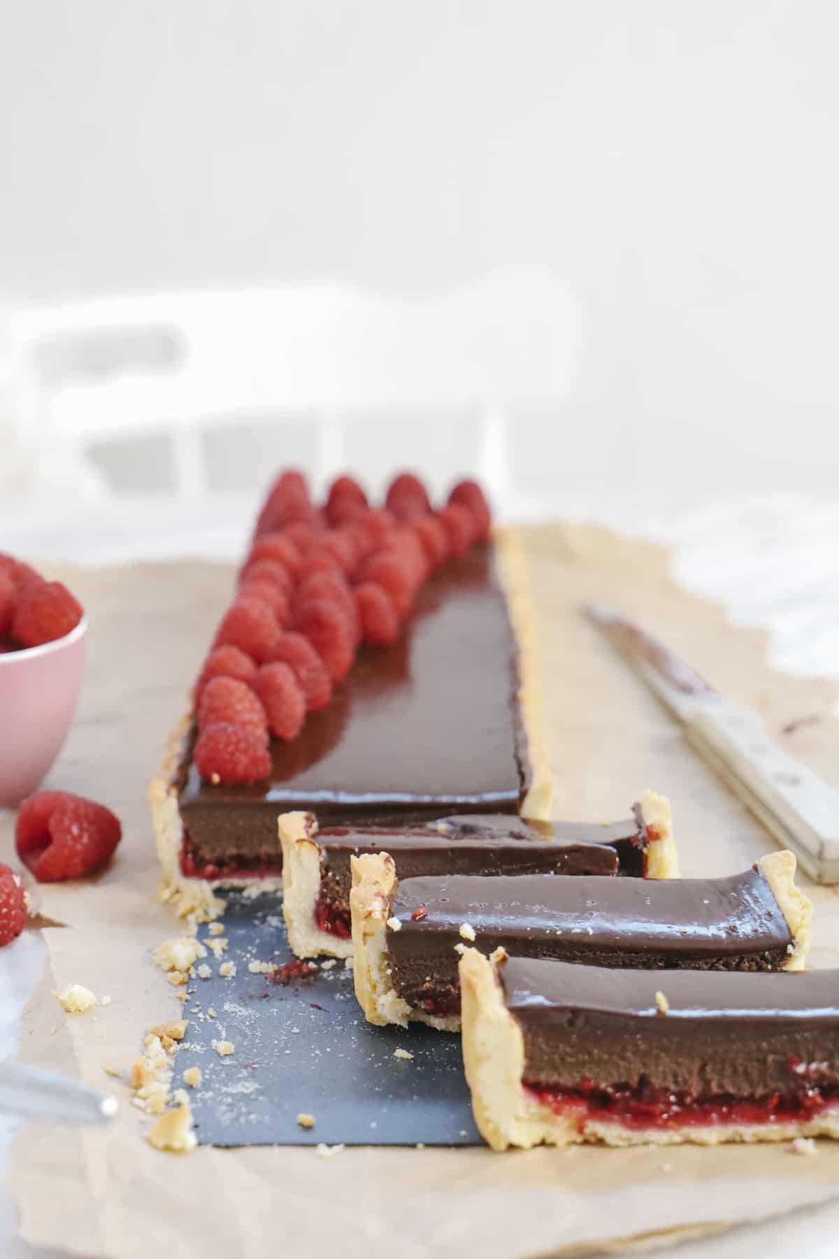 Slicing a chocolate tart with raspberries