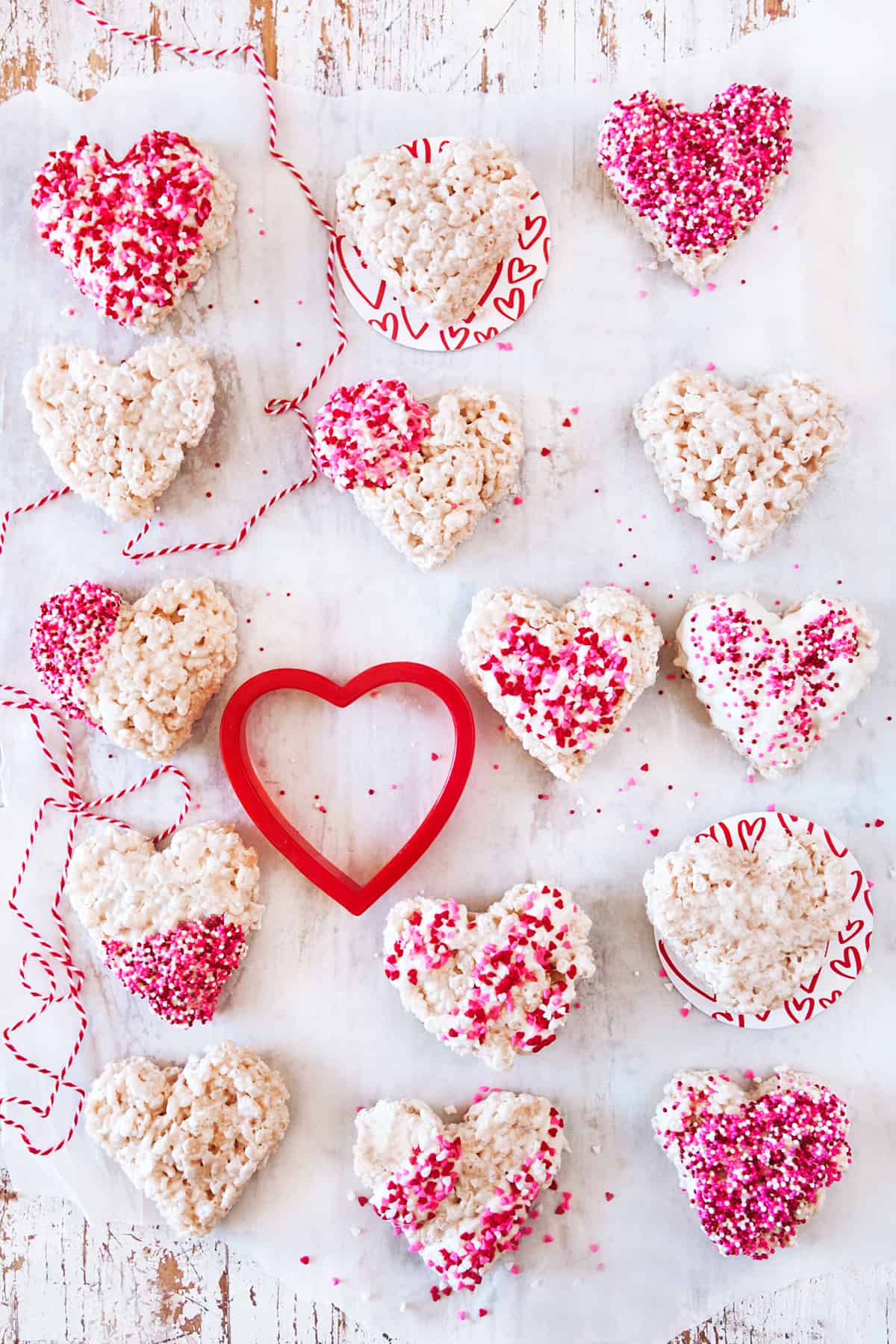 Heart shaped rice Krispie treats with a heart cookie cutter and red and white string. 