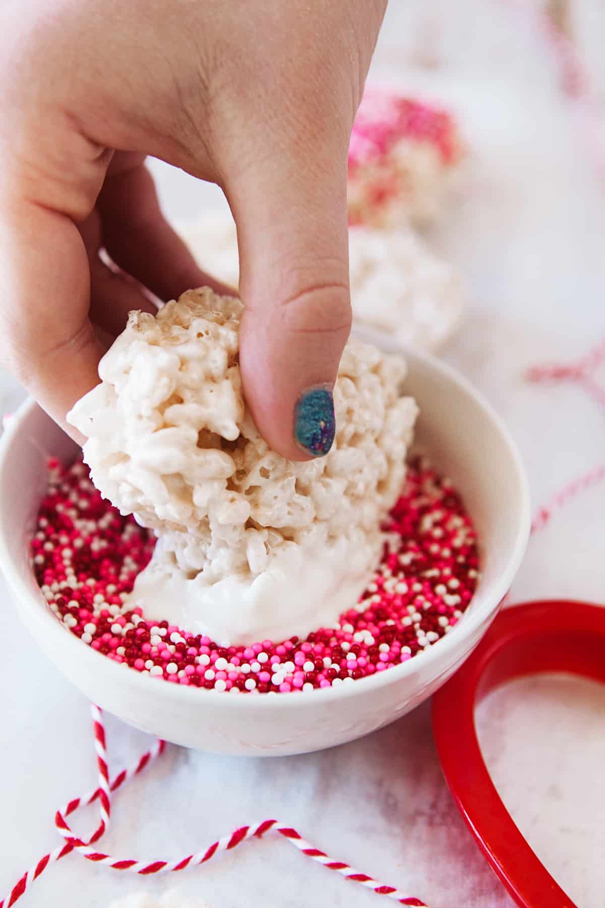 Dipping rice Krispies in sprinkles. 