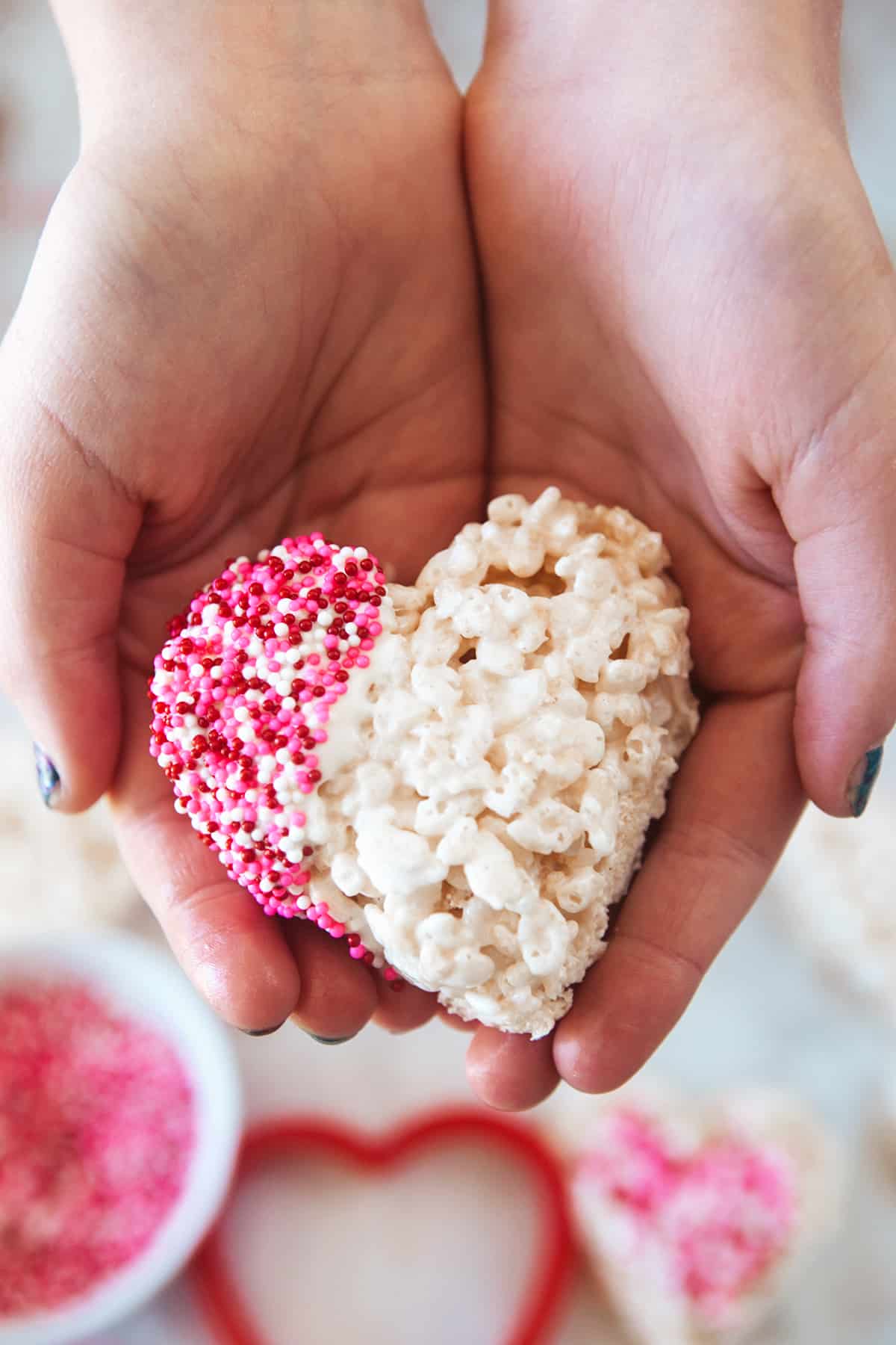 Hands holding a heart rice Krispie treat. 