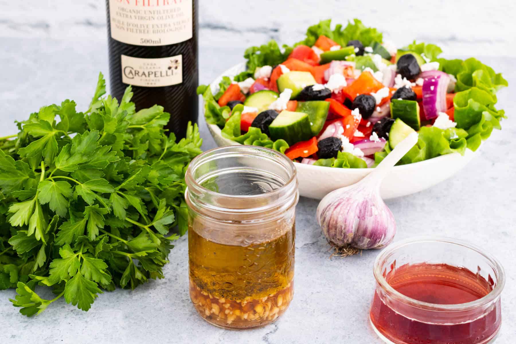 A salad surrounded by red wine dressing ingredients.