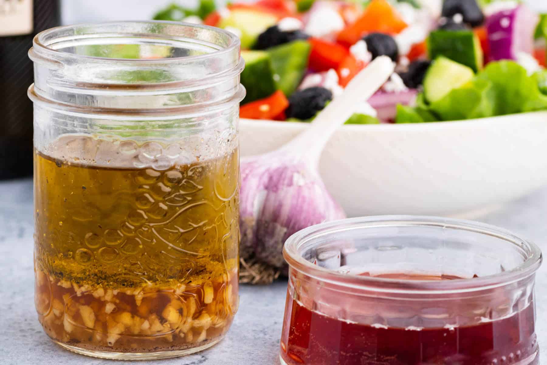 A glass jar containing layers of red wine vinaigrette dressing ingredients.