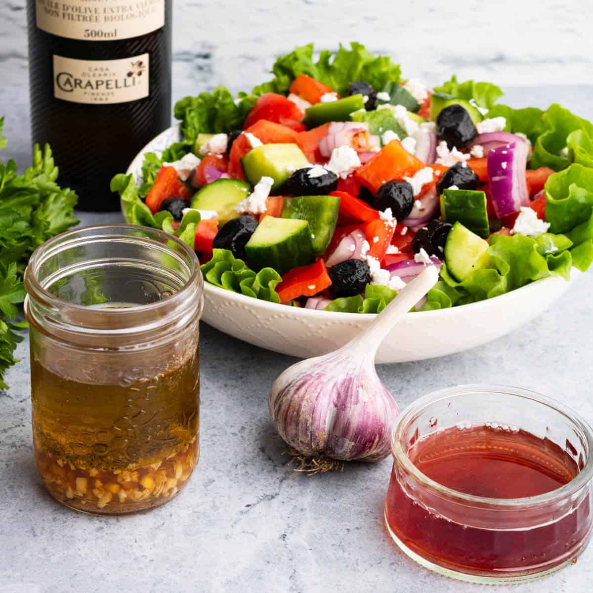 A salad surrounded by red wine dressing ingredients.