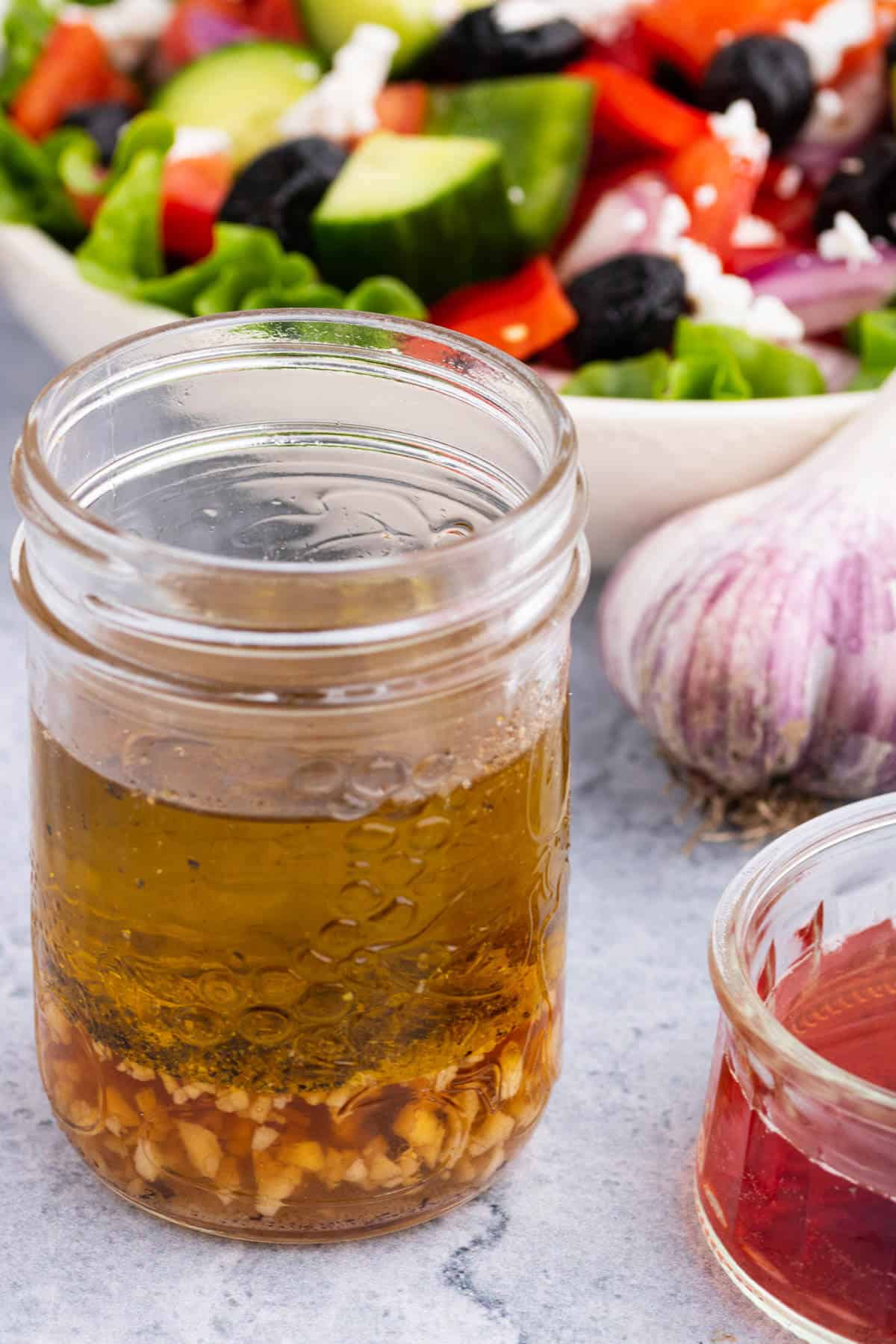 A glass jar containing layers of red wine vinaigrette dressing ingredients.