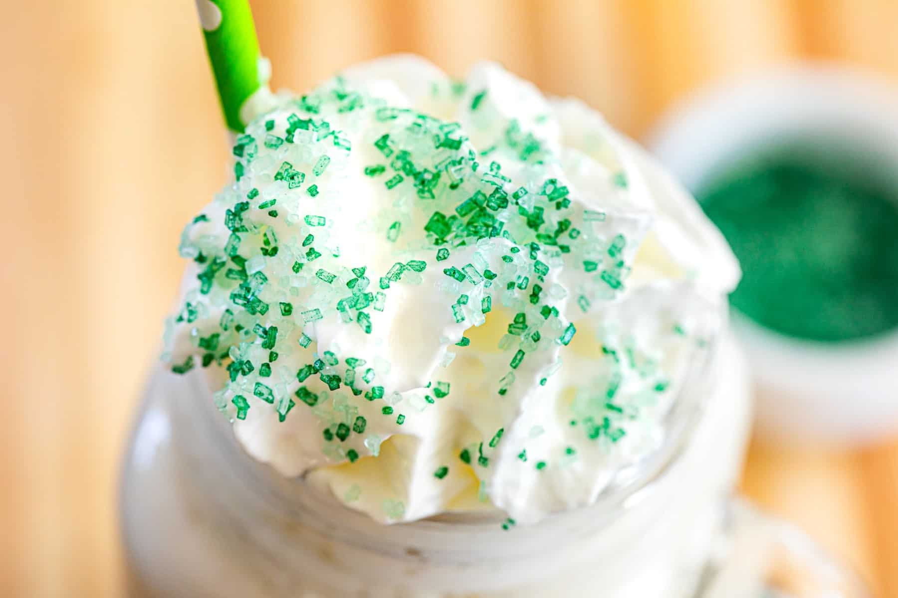 Close up of green sugar sprinkles on whipped cream on an iced coffee