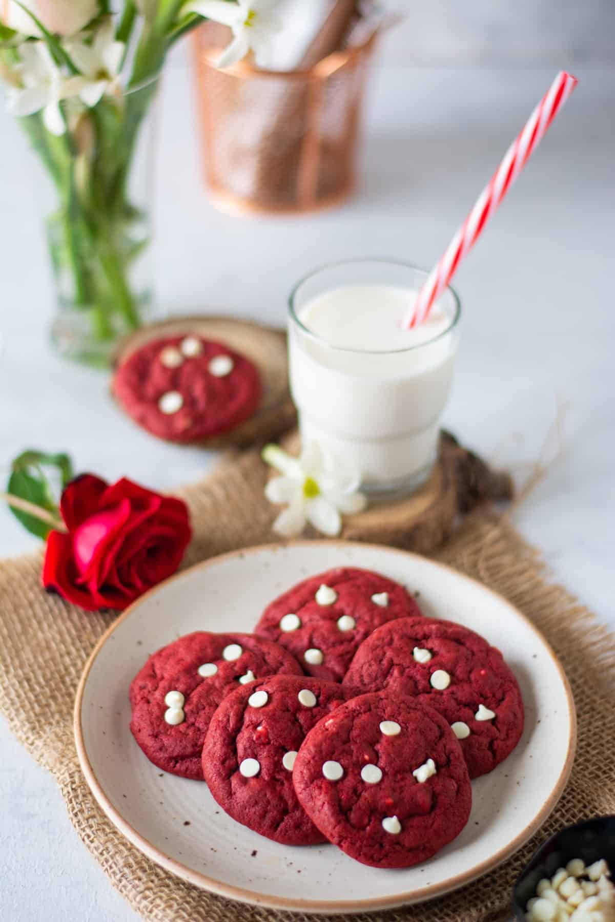 Red Velvet Cookies on a plate with a rose and a glass of milk