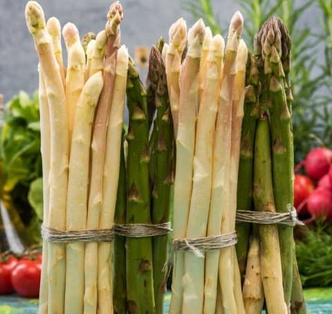 Bunch of asparagus standing on kitchen table.