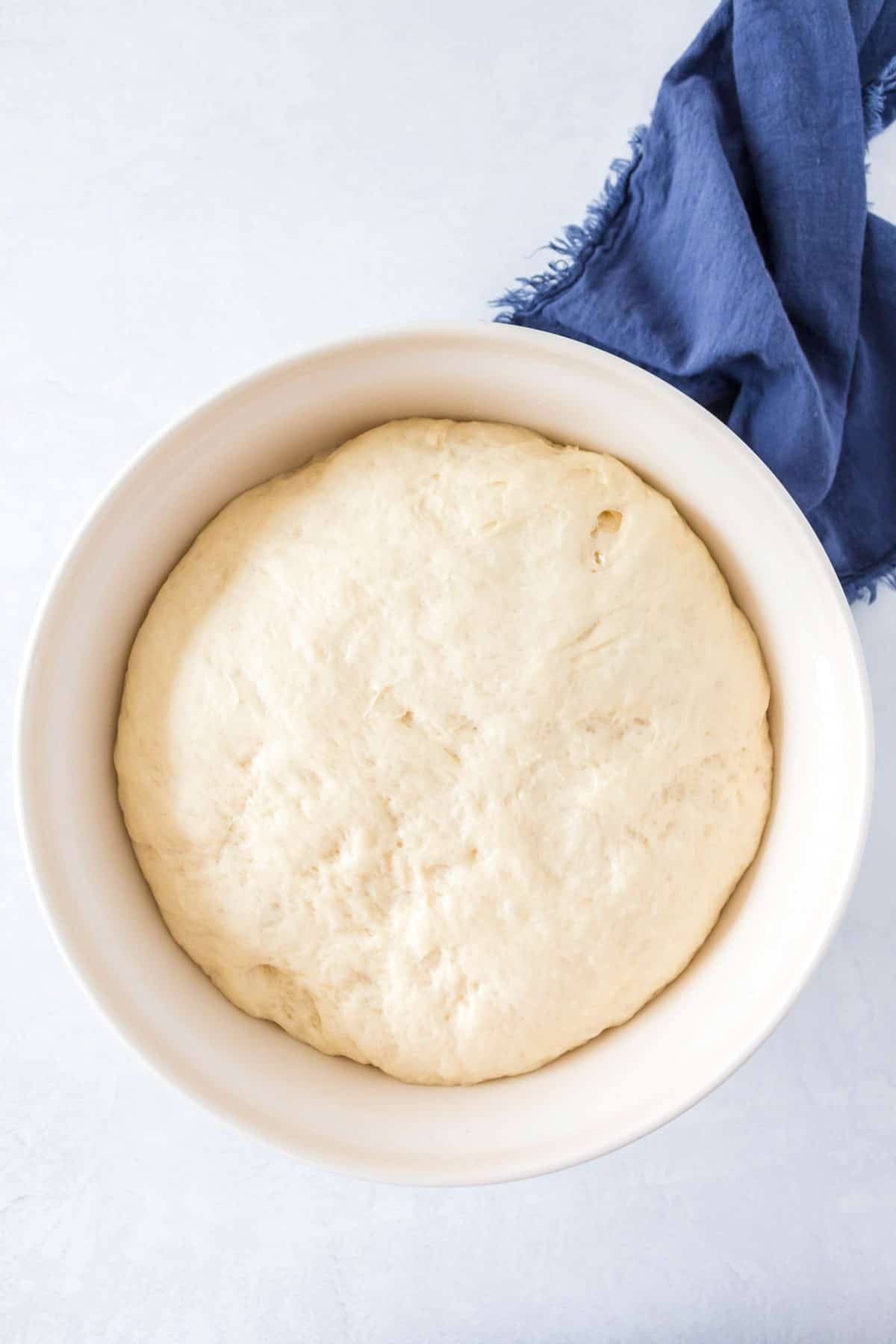 Overhead of bread dough in a white bowl. 