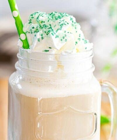 St. Patricks Day Pistachio Iced Coffee in a clear mug with a green adn white straw and green sprinkles