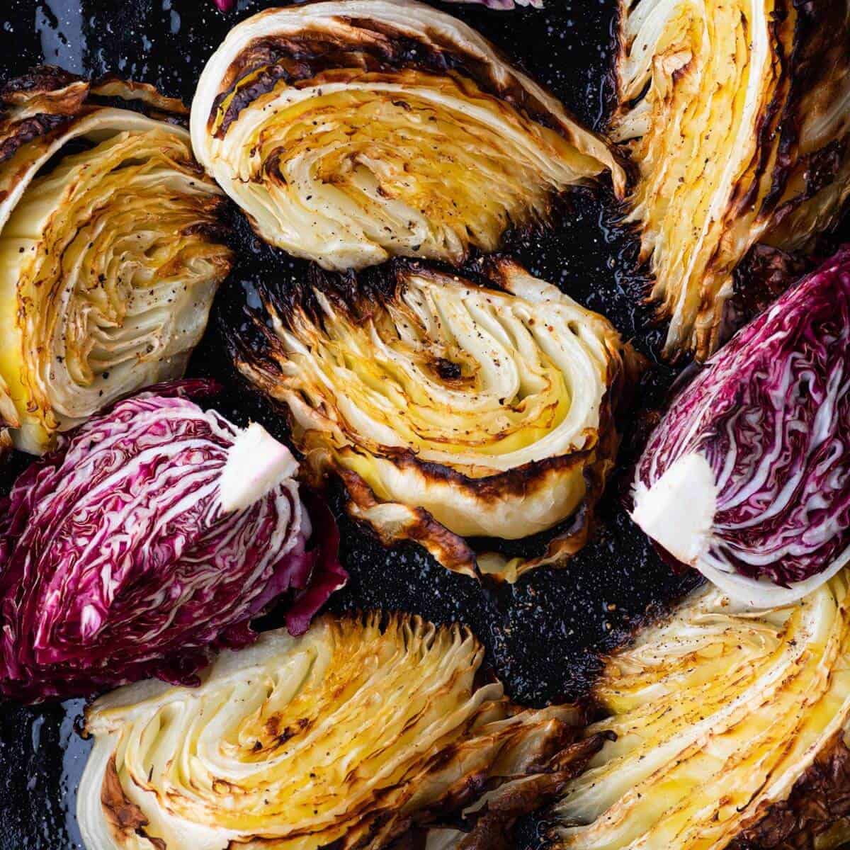 A roasting pan filled with roasted cabbage wedges and purple radicchio. 