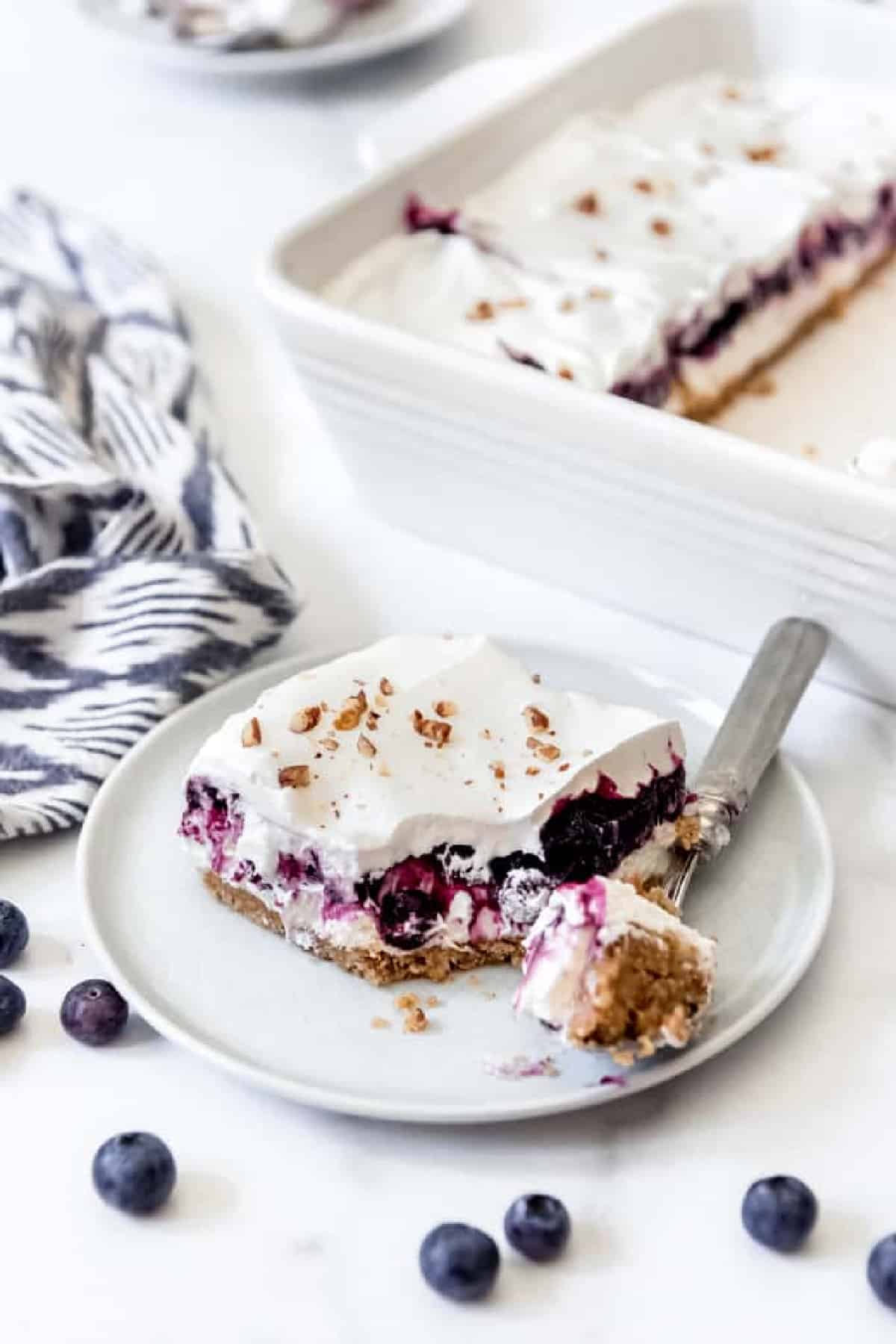 Blueberry Delight on a plate with a fork and a pan in the background with more. 
