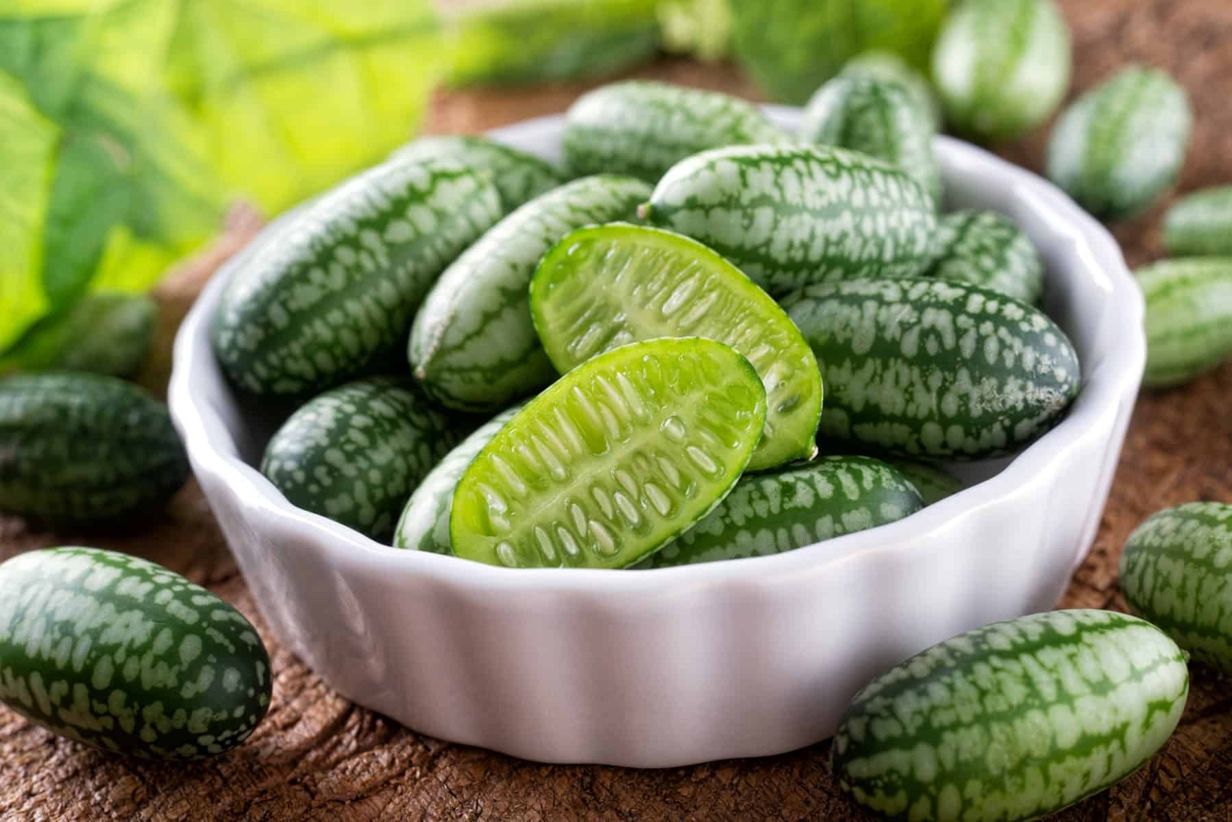 Freshly harvested cucamelons in bowl on a rustic wood table.