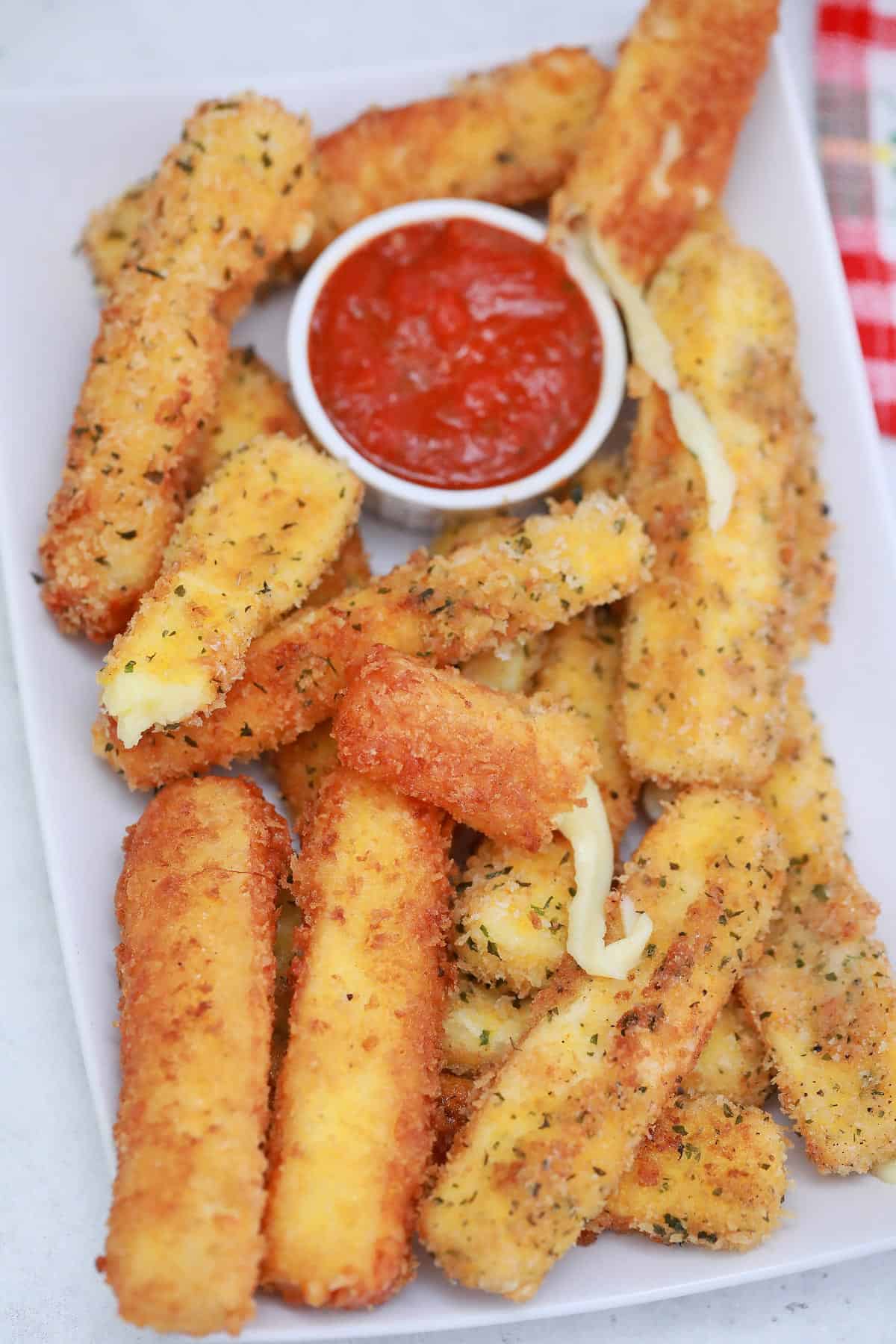 Golden fried mozzarella sticks and tomato dipping sauce, shot from overhead. 