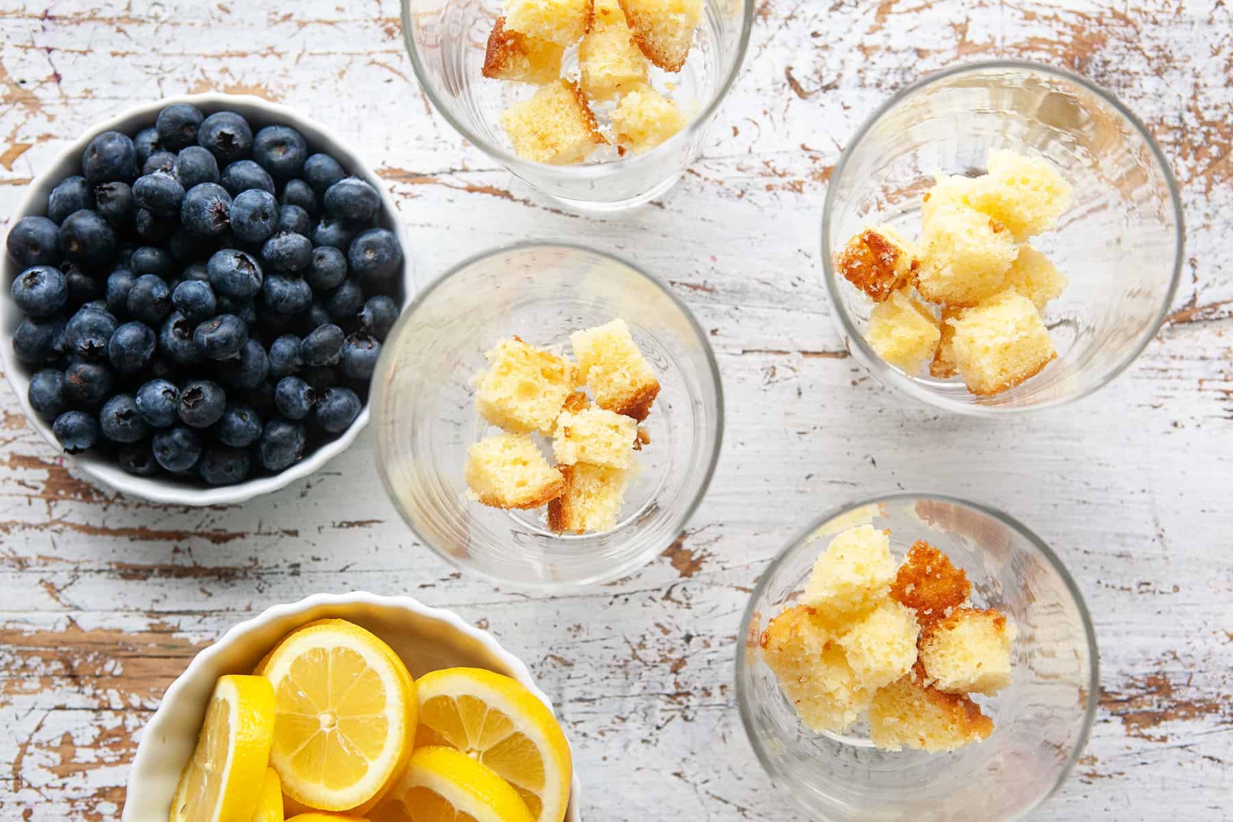 Pound cake in glasses with blueberries and lemons on the side. 