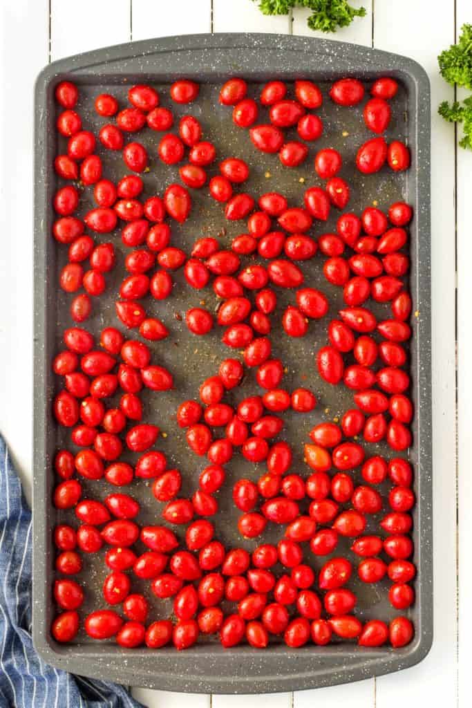 Grape tomatoes on a sheet pan with spices and oil