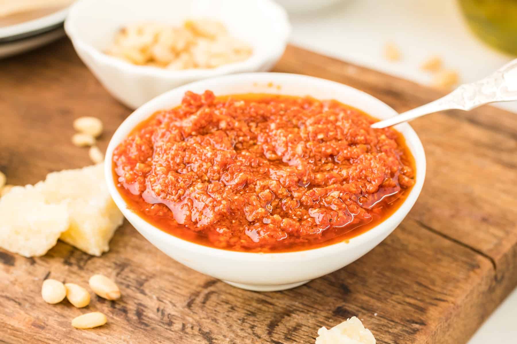 Bowl of red pesto with a spoon. 