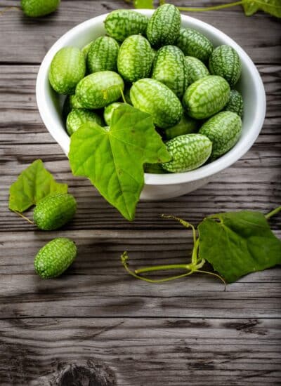 Cucamelons in a white bowl on a wood background.