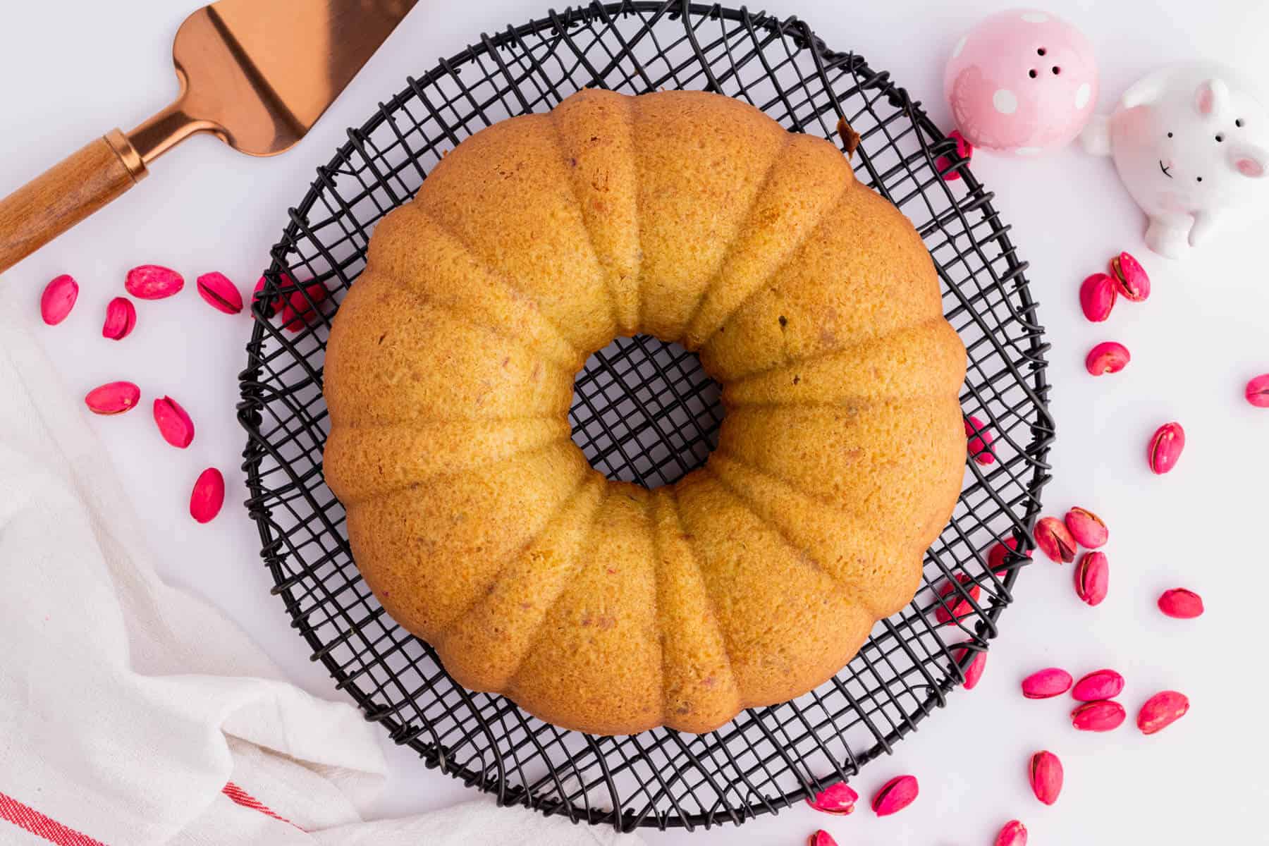 A golden baked bundt cake cooling on a round cake rack.